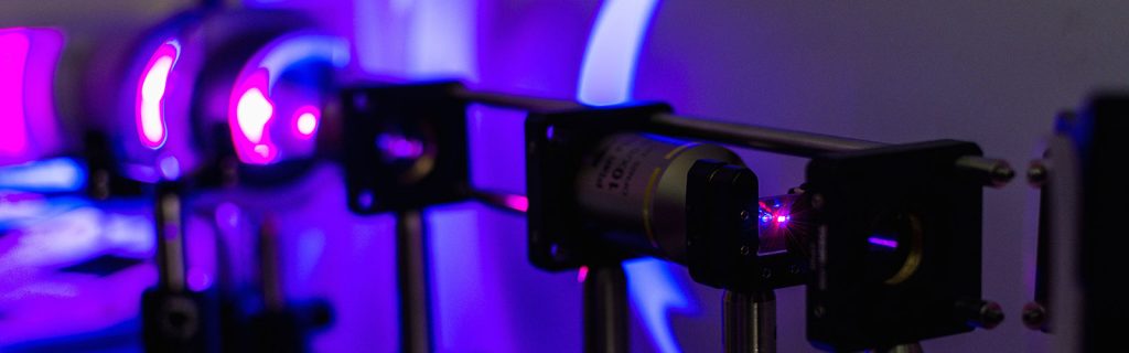 A series of lasers pointing a purple beam towards a focal point on the left